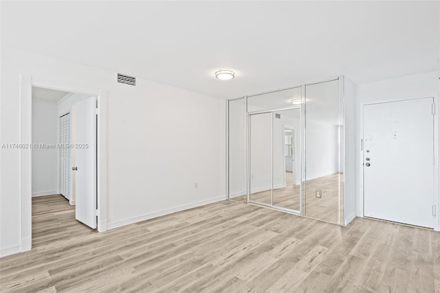 unfurnished bedroom with baseboards, light wood finished floors, and visible vents