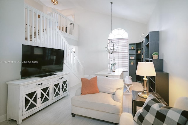 living room featuring light wood-type flooring, a notable chandelier, and high vaulted ceiling