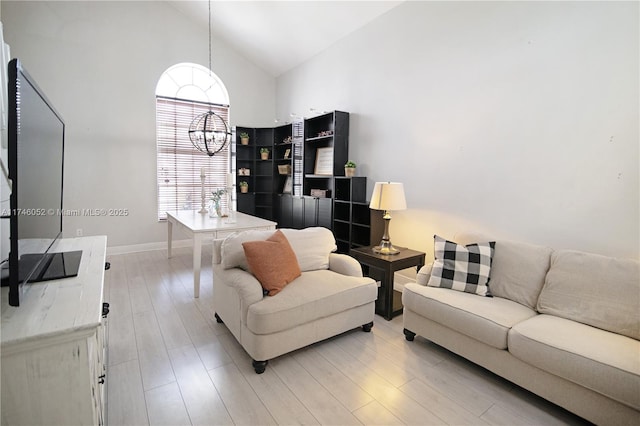 living room with an inviting chandelier, high vaulted ceiling, and light hardwood / wood-style floors