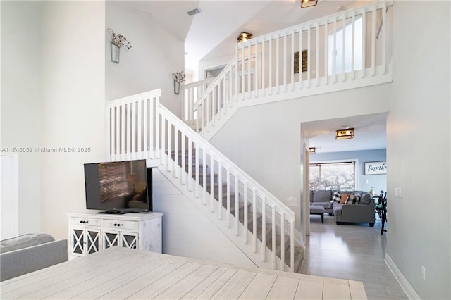 stairs featuring wood-type flooring and a high ceiling