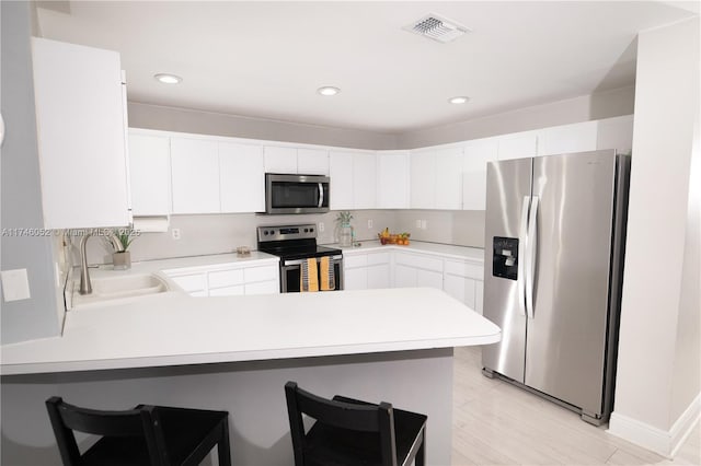 kitchen with stainless steel appliances, kitchen peninsula, sink, and white cabinets