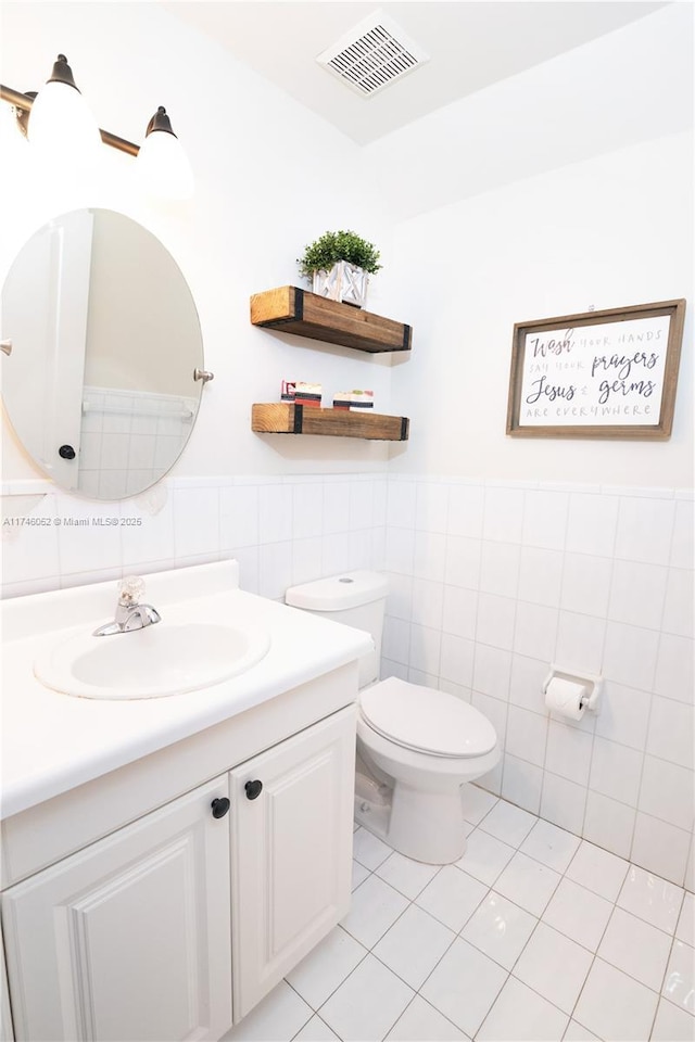 bathroom with tile patterned floors, vanity, toilet, and tile walls