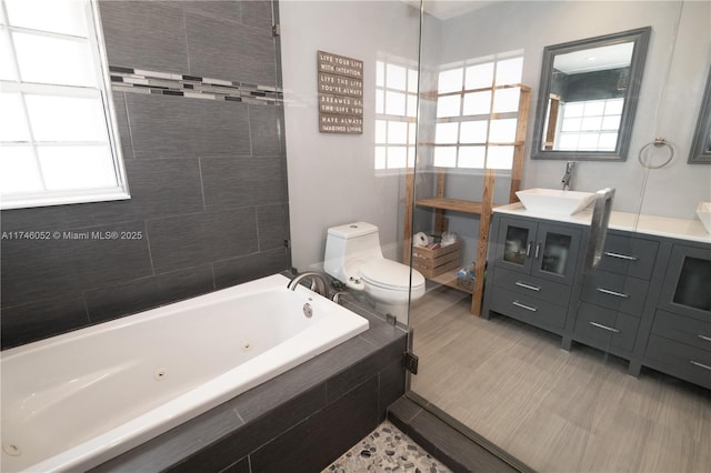 bathroom featuring tiled tub, vanity, a wealth of natural light, and toilet