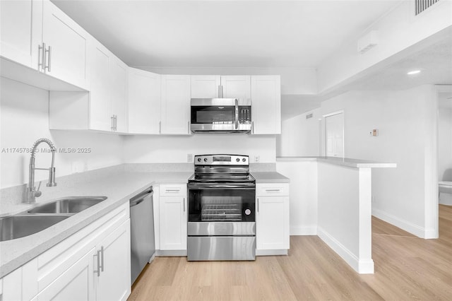 kitchen featuring stainless steel appliances, sink, white cabinets, and light hardwood / wood-style floors