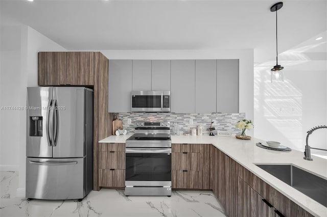 kitchen with tasteful backsplash, sink, decorative light fixtures, and appliances with stainless steel finishes