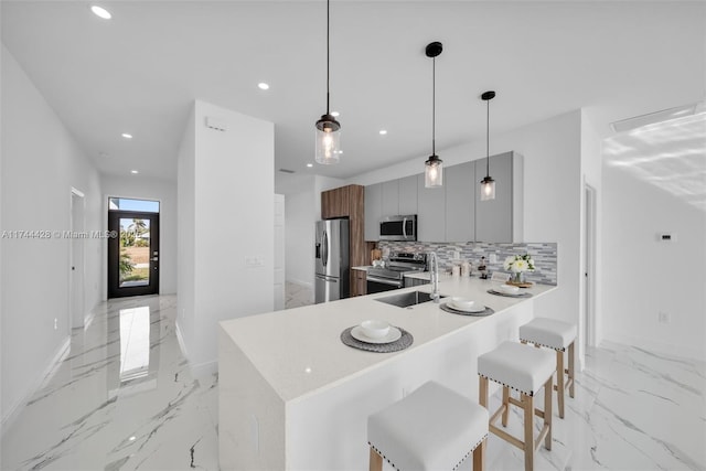 kitchen with appliances with stainless steel finishes, pendant lighting, tasteful backsplash, a breakfast bar area, and kitchen peninsula