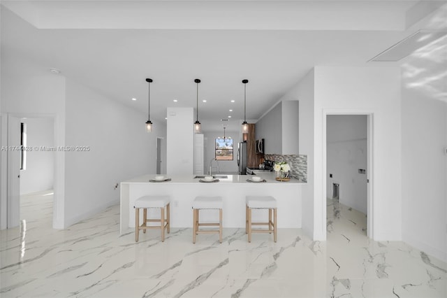 kitchen with a kitchen bar, sink, hanging light fixtures, kitchen peninsula, and decorative backsplash