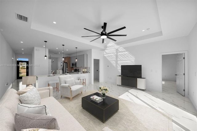 living room featuring ceiling fan and a tray ceiling