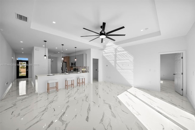 unfurnished living room featuring ceiling fan and a tray ceiling