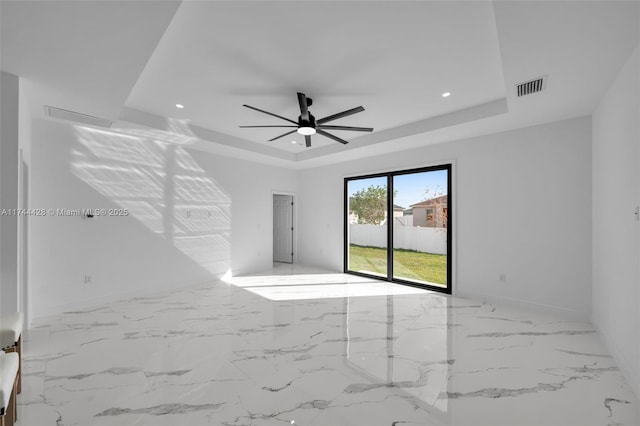 empty room featuring ceiling fan and a tray ceiling