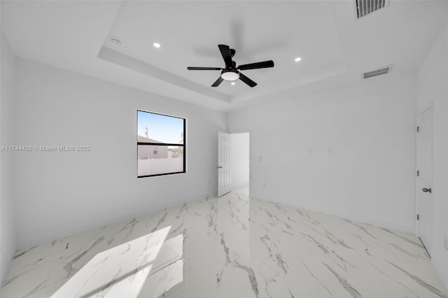 unfurnished room with ceiling fan and a tray ceiling