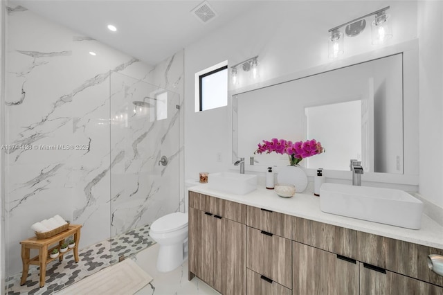 bathroom featuring vanity, toilet, and tiled shower