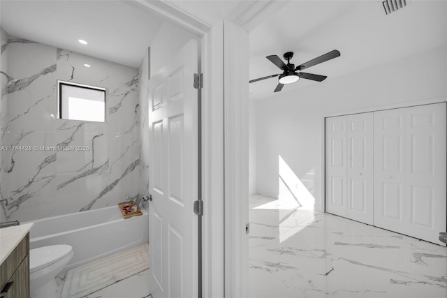 full bathroom featuring vanity, ceiling fan, tiled shower / bath, and toilet