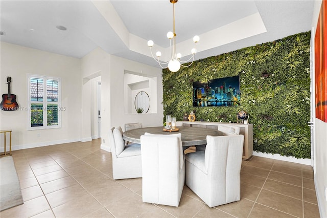 dining space featuring tile patterned flooring, a notable chandelier, and a tray ceiling