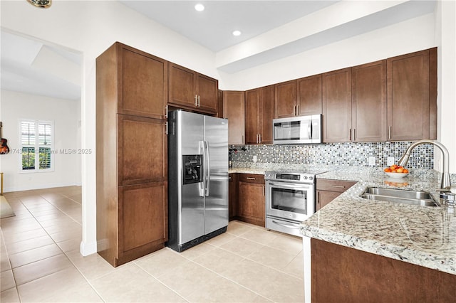 kitchen featuring light tile patterned flooring, tasteful backsplash, sink, light stone counters, and stainless steel appliances