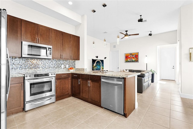 kitchen with appliances with stainless steel finishes, tasteful backsplash, sink, hanging light fixtures, and kitchen peninsula