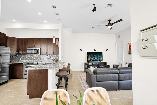 kitchen with appliances with stainless steel finishes, sink, a kitchen breakfast bar, hanging light fixtures, and light stone countertops