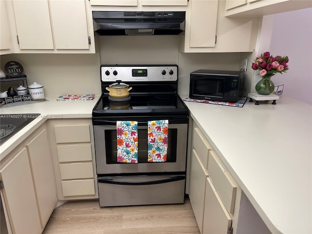 8290 Lake Dr Unit 223, Doral, FL 33166 - kitchen featuring light countertops, stainless steel electric range, under cabinet range hood, black microwave, and light wood-type flooring