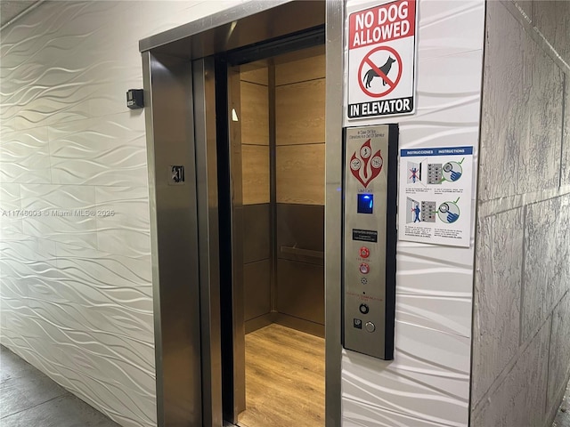 interior details featuring elevator and hardwood / wood-style floors