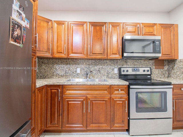 kitchen featuring appliances with stainless steel finishes, sink, backsplash, and light stone counters