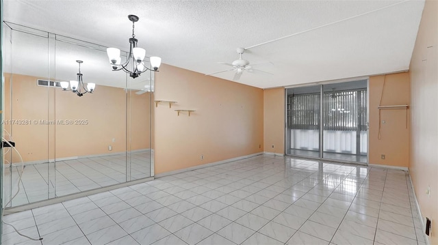 empty room featuring ceiling fan with notable chandelier, floor to ceiling windows, a textured ceiling, and light tile patterned flooring