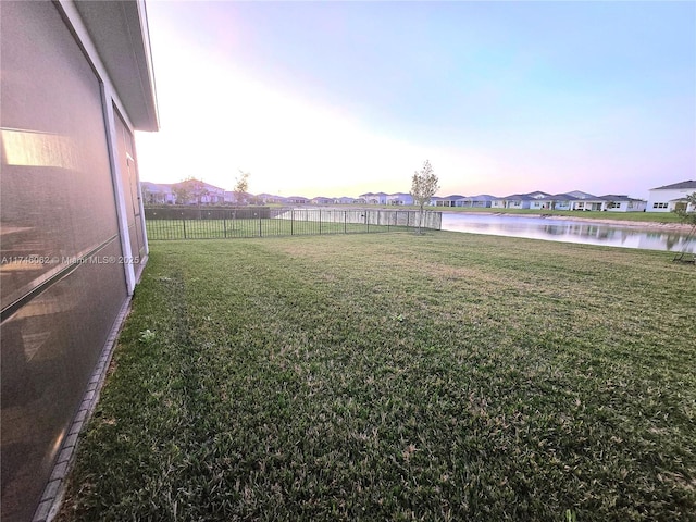 yard at dusk featuring a water view