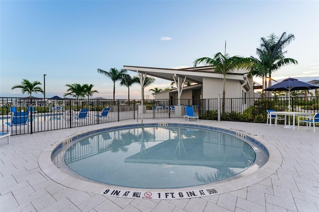 pool at dusk featuring a patio area