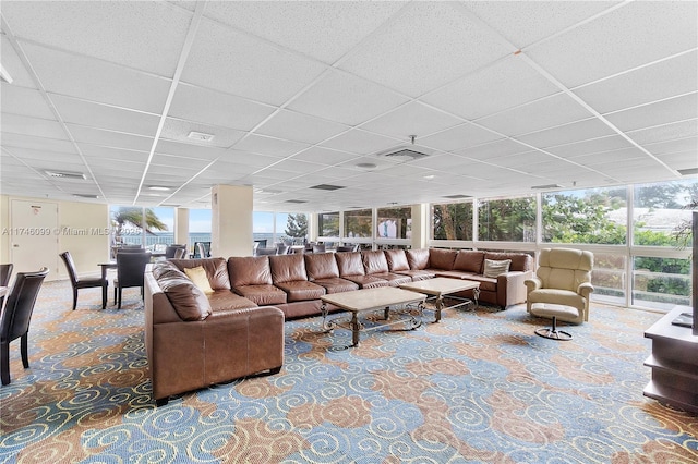 living room with expansive windows, a paneled ceiling, and a wealth of natural light