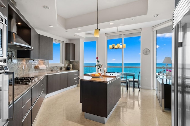 kitchen featuring pendant lighting, a water view, stainless steel gas stovetop, and a kitchen island