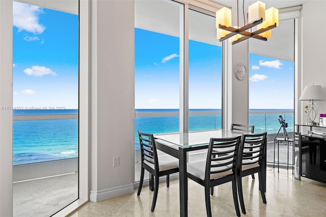 dining room featuring a water view, a chandelier, and a view of the beach