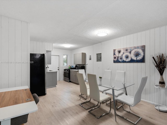 dining area featuring sink, light hardwood / wood-style floors, and a textured ceiling