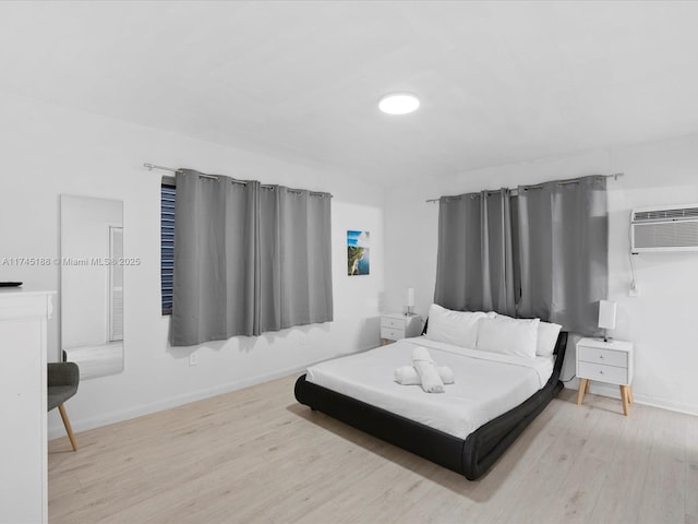 bedroom featuring a wall mounted air conditioner and light hardwood / wood-style flooring