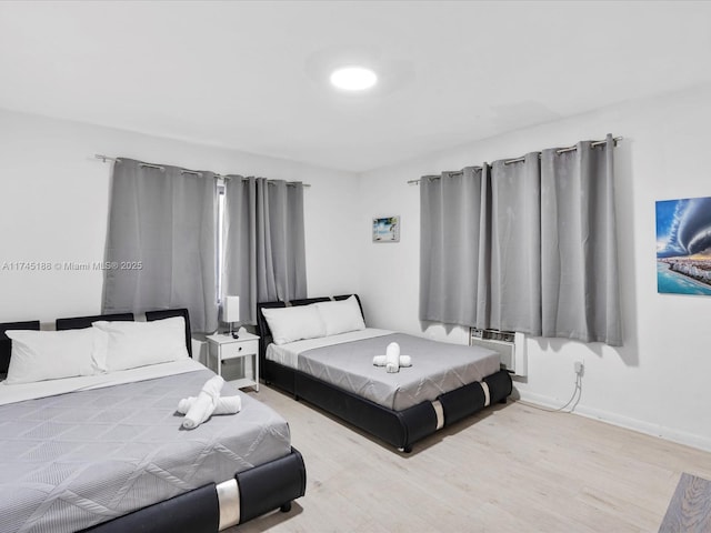 bedroom featuring light hardwood / wood-style floors and a wall unit AC