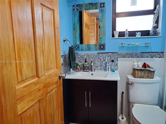 bathroom featuring vanity, toilet, tile walls, and backsplash