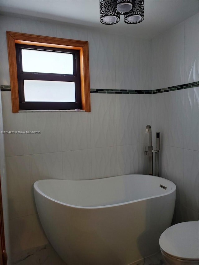 bathroom with a washtub, tile walls, and toilet