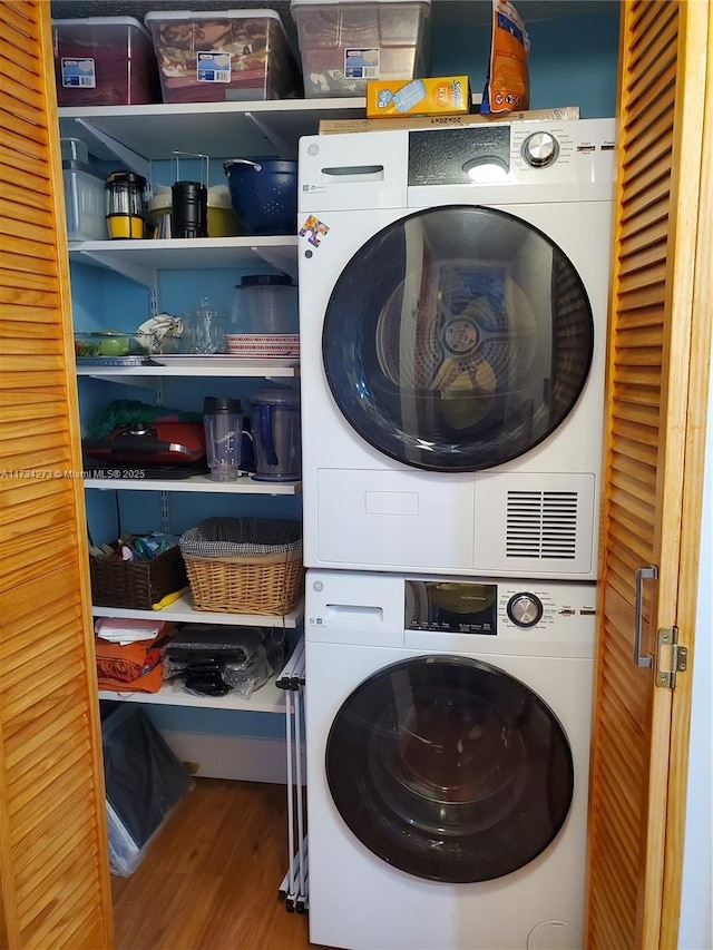 washroom featuring hardwood / wood-style flooring and stacked washer / drying machine