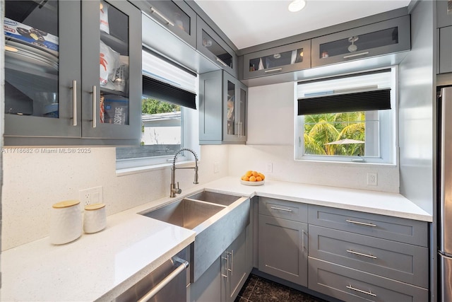 kitchen featuring sink, gray cabinetry, light stone counters, stainless steel fridge, and backsplash