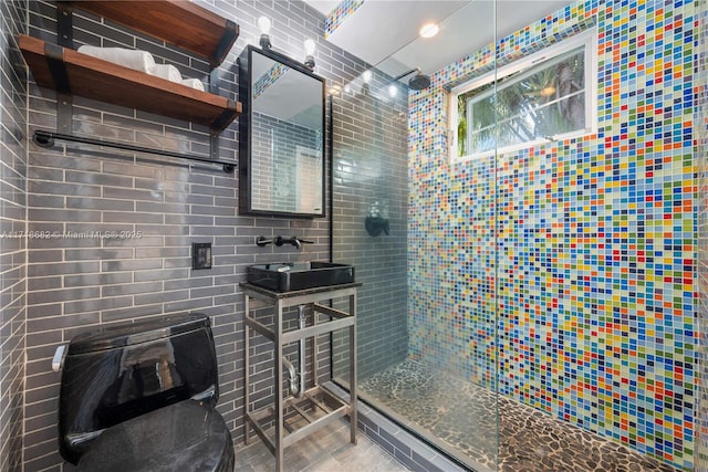 bathroom featuring tiled shower, sink, and tile walls