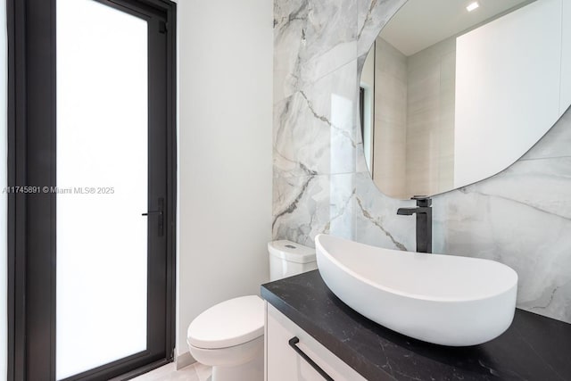 bathroom featuring vanity, tile walls, and toilet