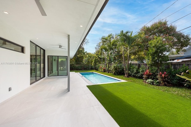 view of swimming pool with ceiling fan, a patio area, and a lawn