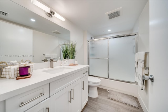 full bathroom with vanity, hardwood / wood-style floors, enclosed tub / shower combo, and toilet