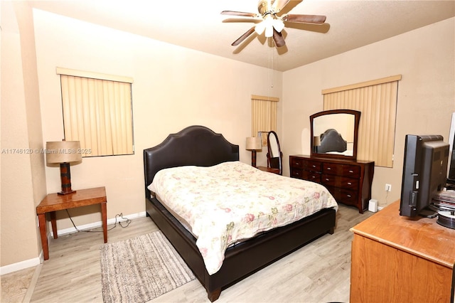 bedroom featuring a ceiling fan, light wood-style flooring, and baseboards