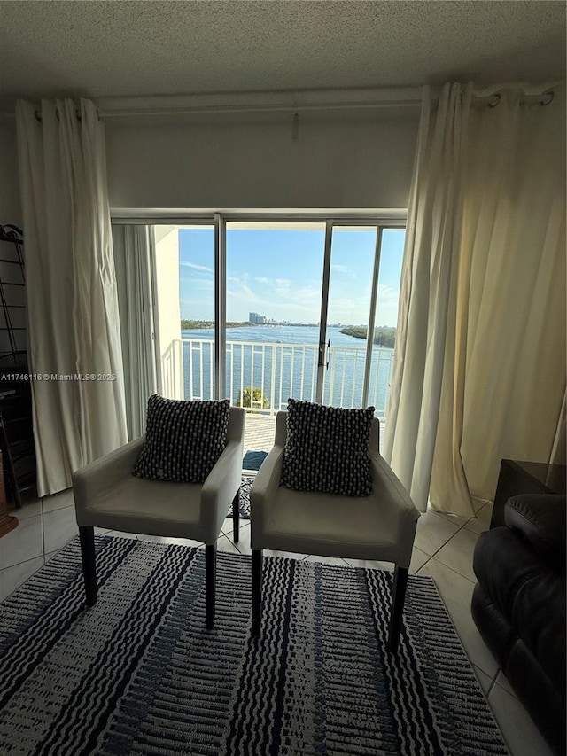 tiled living room with a water view, plenty of natural light, and a textured ceiling