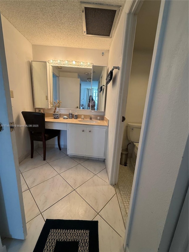 bathroom featuring vanity, toilet, and a textured ceiling