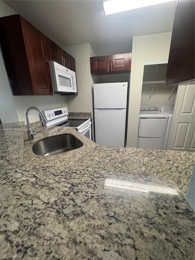 kitchen with separate washer and dryer, sink, light stone counters, and white appliances