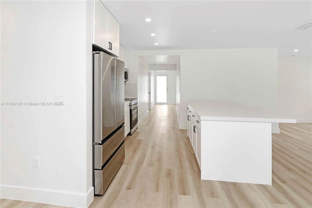 kitchen featuring appliances with stainless steel finishes, a center island, white cabinets, and light hardwood / wood-style flooring