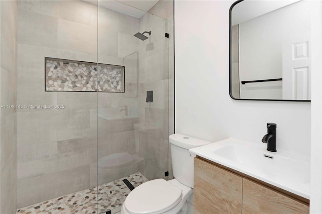 bathroom with vanity, toilet, and a tile shower