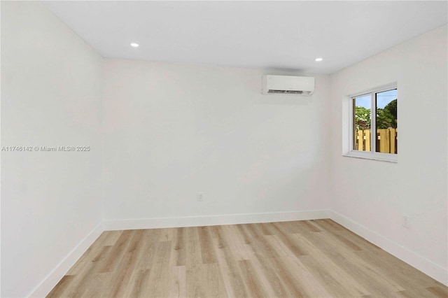 empty room with a wall mounted air conditioner and light hardwood / wood-style floors