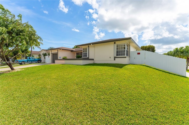 view of front of house with a front yard, fence, driveway, and an attached garage