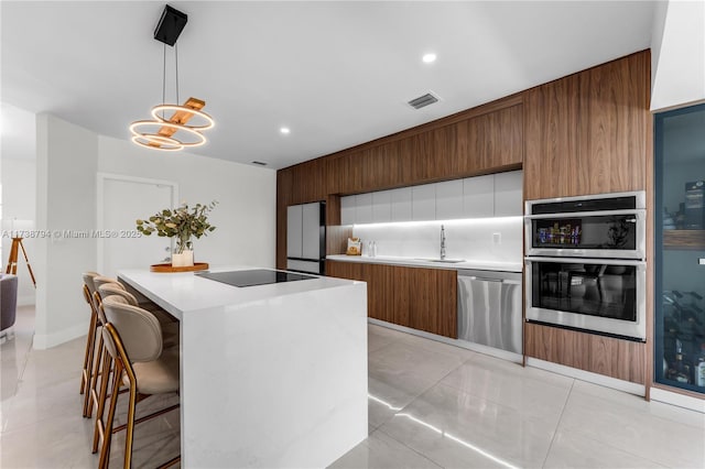 kitchen with light countertops, appliances with stainless steel finishes, modern cabinets, and pendant lighting